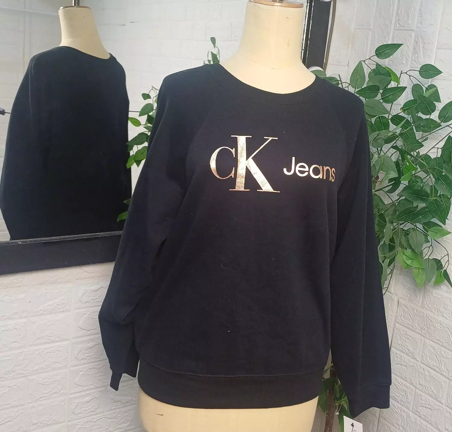 a black Calvin Klein Jeans crewneck sweatshirt featuring a gold metallic logo